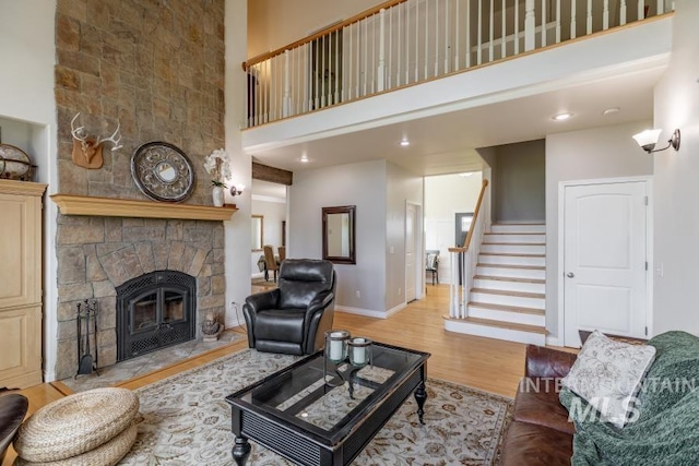 1027 Larkspur, Moscow, ID 83843 - living room featuring a towering ceiling, light wood-style floors, stairway, a stone fireplace, and baseboards