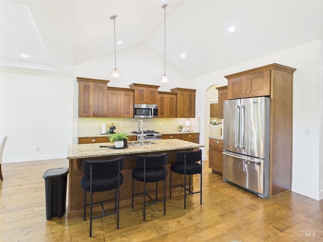 9389 W Wildbranch, Star, ID 83669 - kitchen with stainless steel appliances, a breakfast bar, brown cabinetry, light stone countertops, and pendant lighting