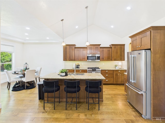 9389 W Wildbranch, Star, ID 83669 - kitchen with stainless steel appliances, a sink, a kitchen bar, light wood finished floors, and brown cabinets