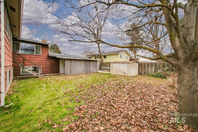 view of yard with an outdoor structure, fence, and a shed