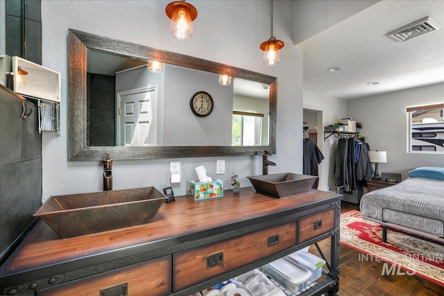 1011 Filer Ave W, Twin Falls, ID 83301 - bathroom with wood finished floors, double vanity, a textured ceiling, and a textured wall