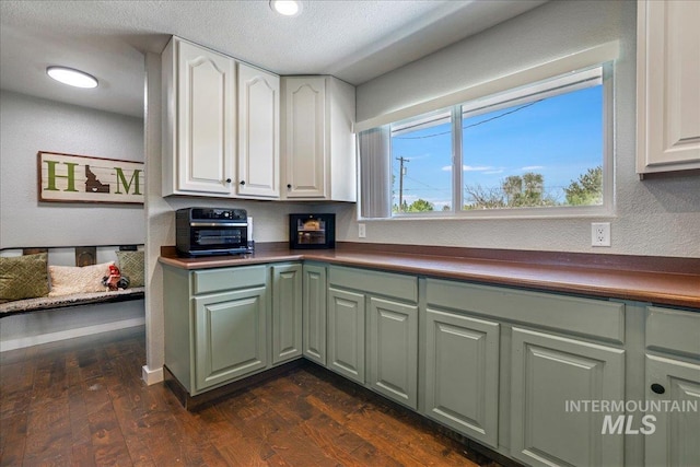 1011 Filer Ave W, Twin Falls, ID 83301 - kitchen featuring green cabinetry, dark wood-type flooring, dark countertops, a textured ceiling, and a textured wall