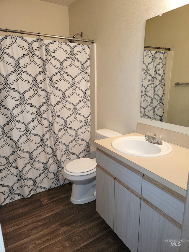 bathroom featuring toilet, vanity, a shower with curtain, and wood finished floors