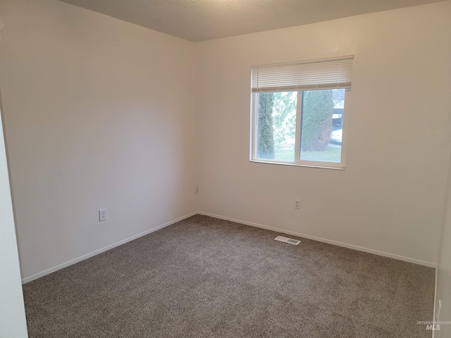 empty room featuring visible vents, baseboards, and carpet