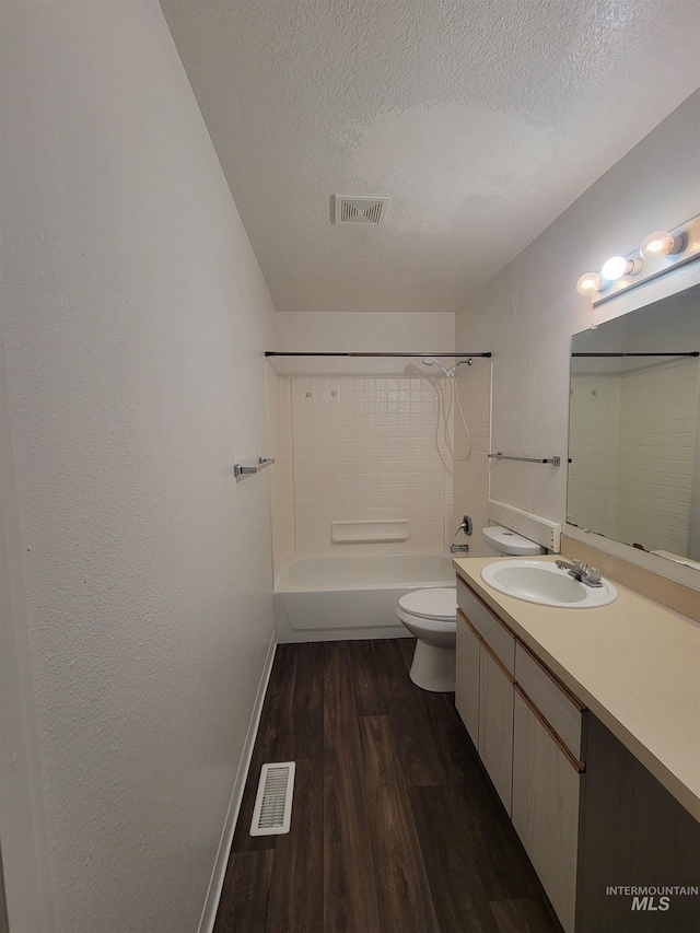 bathroom with visible vents, toilet, a textured ceiling, and wood finished floors