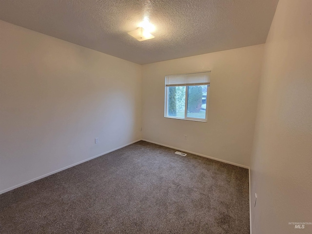 spare room featuring dark colored carpet, baseboards, and a textured ceiling