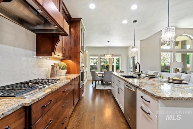 6964 N Moon Drummer Way, Meridian, ID 83646 - kitchen featuring wall chimney exhaust hood, appliances with stainless steel finishes, a sink, a chandelier, and dark wood-type flooring