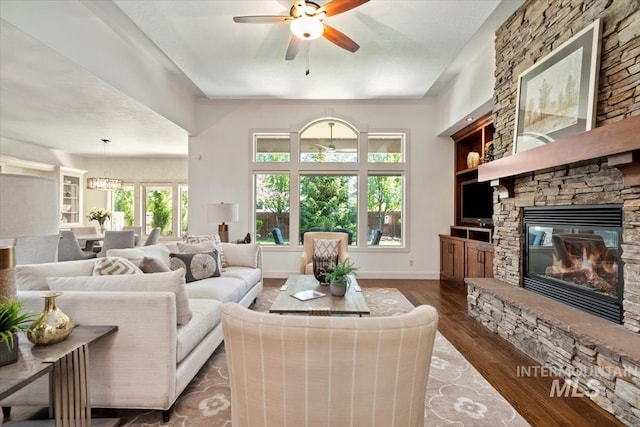 6964 N Moon Drummer Way, Meridian, ID 83646 - living room featuring ceiling fan, a stone fireplace, wood finished floors, a chandelier, and baseboards