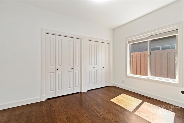 6964 N Moon Drummer Way, Meridian, ID 83646 - unfurnished bedroom with multiple closets, dark wood-type flooring, and baseboards