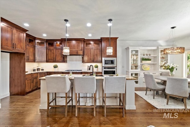 6964 N Moon Drummer Way, Meridian, ID 83646 - kitchen featuring stainless steel appliances, a sink, a kitchen breakfast bar, glass insert cabinets, and recessed lighting