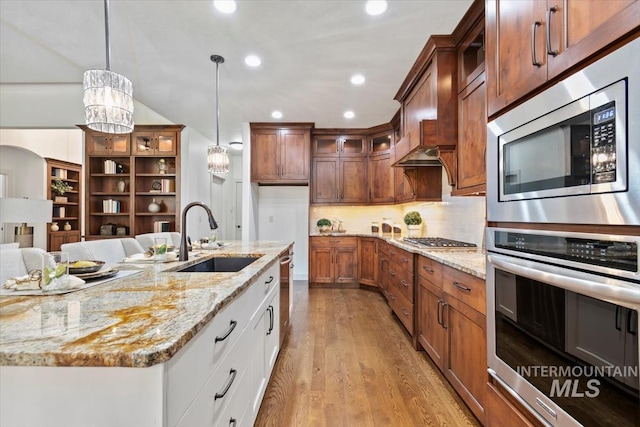 6964 N Moon Drummer Way, Meridian, ID 83646 - kitchen featuring appliances with stainless steel finishes, a sink, glass insert cabinets, light wood-type flooring, and light stone counters