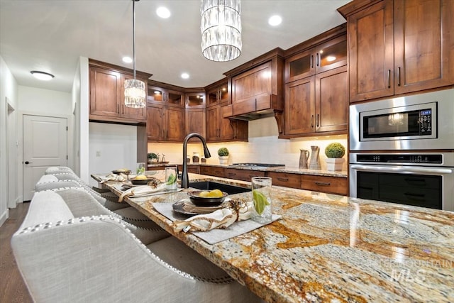 6964 N Moon Drummer Way, Meridian, ID 83646 - kitchen featuring stainless steel appliances, light stone countertops, a sink, glass insert cabinets, and decorative light fixtures