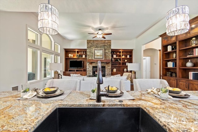 6964 N Moon Drummer Way, Meridian, ID 83646 - kitchen with a ceiling fan, arched walkways, hanging light fixtures, light stone counters, and a chandelier