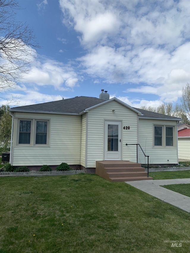 view of front facade featuring a shingled roof, a front lawn, a chimney, and central AC unit