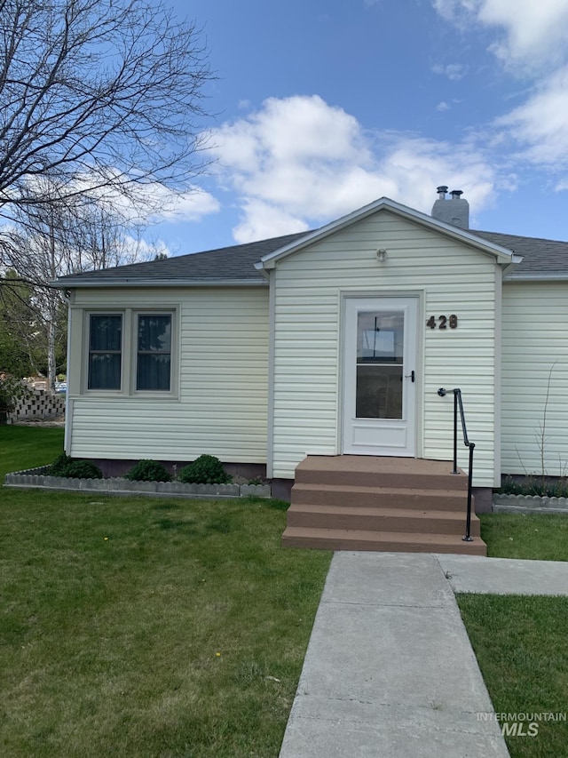 view of front of property featuring roof with shingles, a chimney, and a front yard