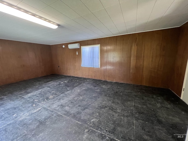 basement featuring a wall unit AC, wooden walls, and dark floors