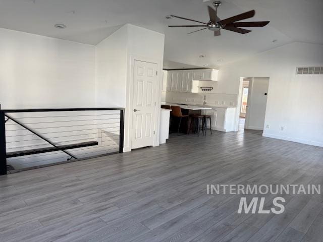 unfurnished living room featuring wood-type flooring, vaulted ceiling, and ceiling fan