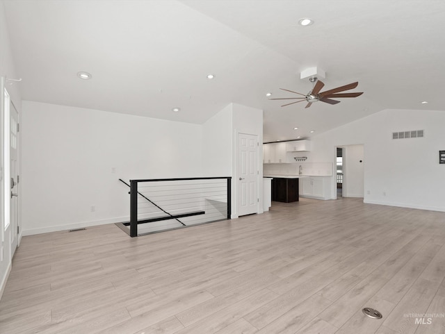 unfurnished living room featuring ceiling fan, lofted ceiling, sink, and light wood-type flooring