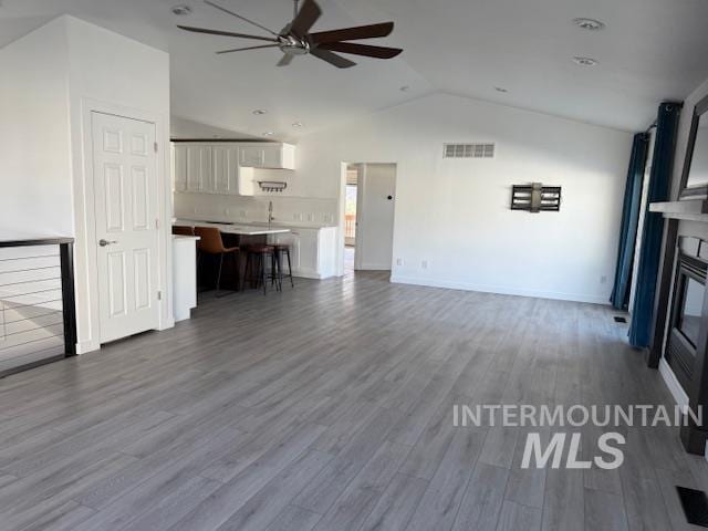 unfurnished living room with vaulted ceiling, hardwood / wood-style floors, and ceiling fan