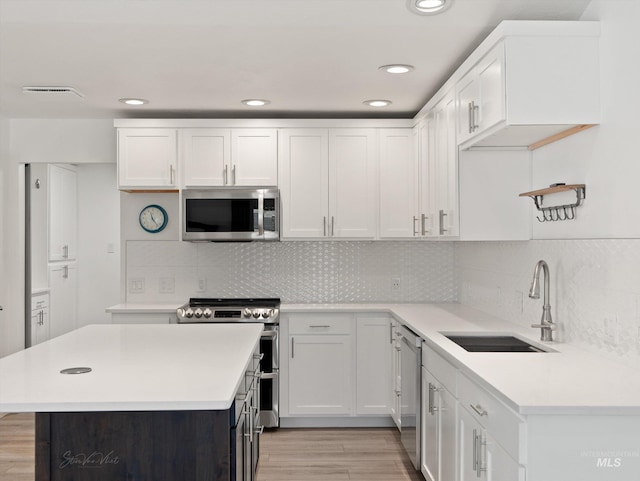 kitchen featuring sink, light hardwood / wood-style flooring, appliances with stainless steel finishes, tasteful backsplash, and white cabinets