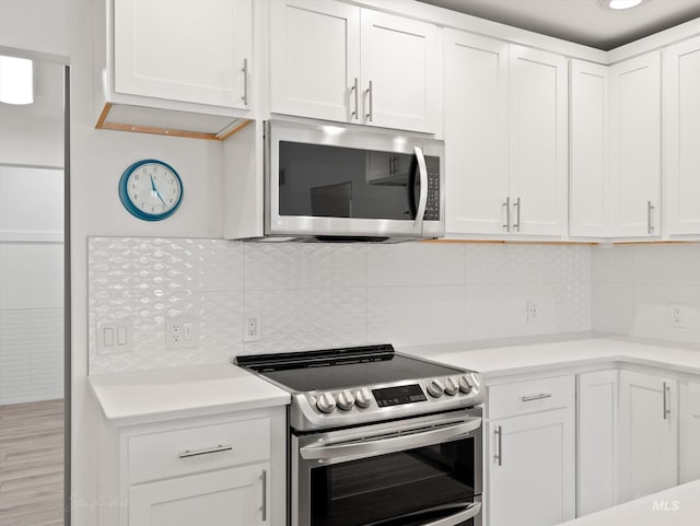 kitchen with decorative backsplash, stainless steel appliances, and white cabinets