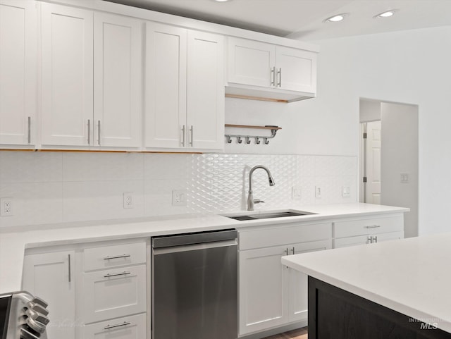 kitchen featuring sink, tasteful backsplash, dishwasher, white cabinets, and stove