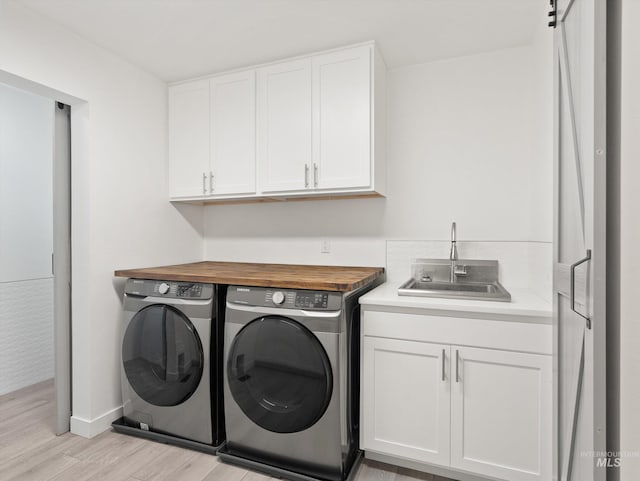 washroom with cabinets, sink, washer and clothes dryer, and light wood-type flooring