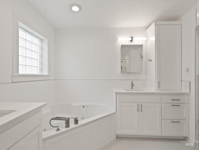 bathroom featuring vanity, a bath, and tile walls