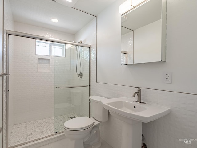 bathroom with toilet, tile walls, and a shower with shower door