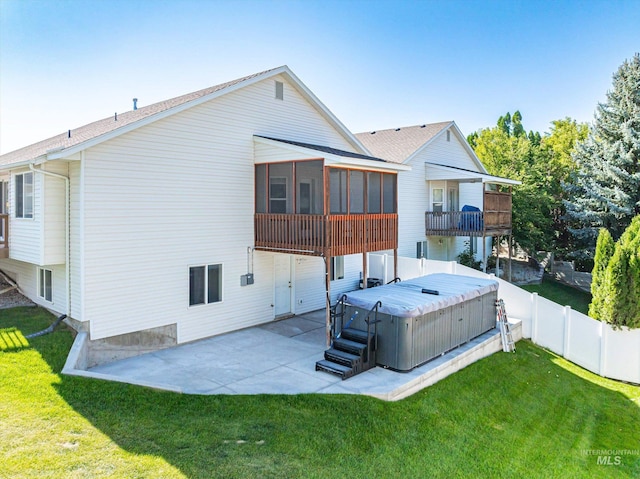 rear view of property with a patio area, a hot tub, a sunroom, and a lawn