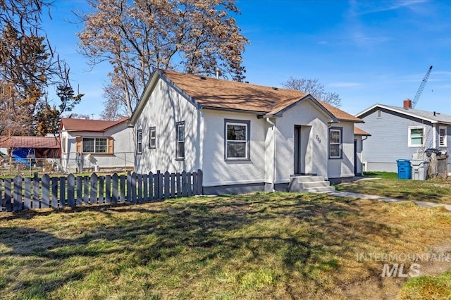 view of front facade with stucco siding, a front lawn, and fence