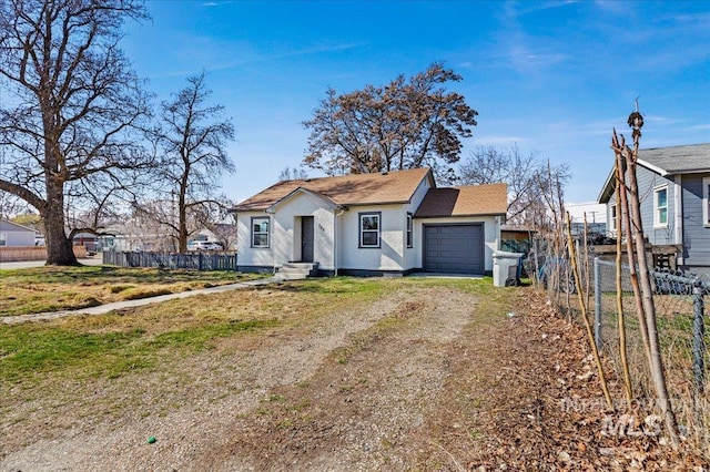 view of front of home with fence, a garage, dirt driveway, and stucco siding