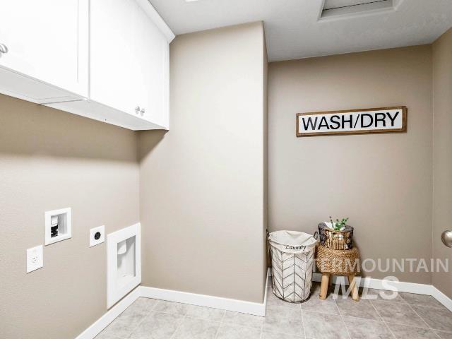 clothes washing area featuring washer hookup, electric dryer hookup, cabinets, and light tile patterned floors