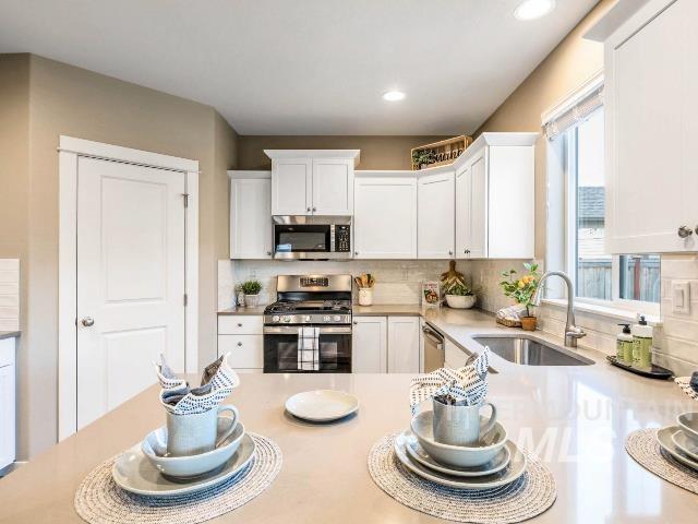 kitchen featuring tasteful backsplash, white cabinetry, sink, and appliances with stainless steel finishes