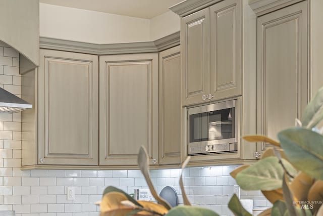 interior space featuring decorative backsplash, stainless steel microwave, and cream cabinetry