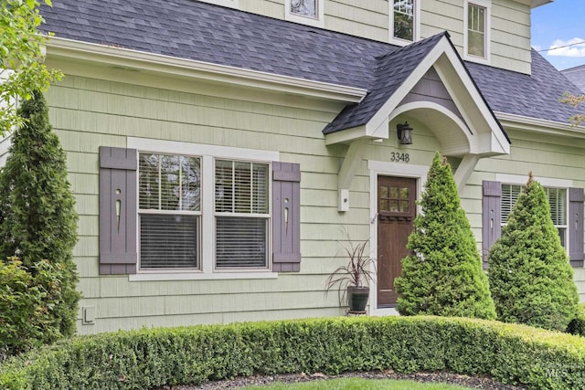 view of exterior entry featuring roof with shingles
