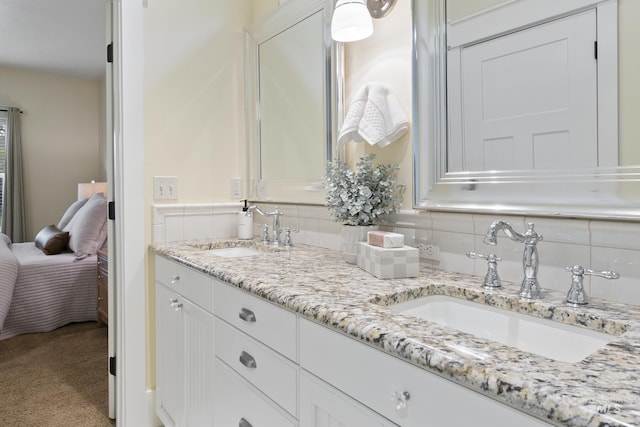 ensuite bathroom featuring double vanity, a sink, and connected bathroom