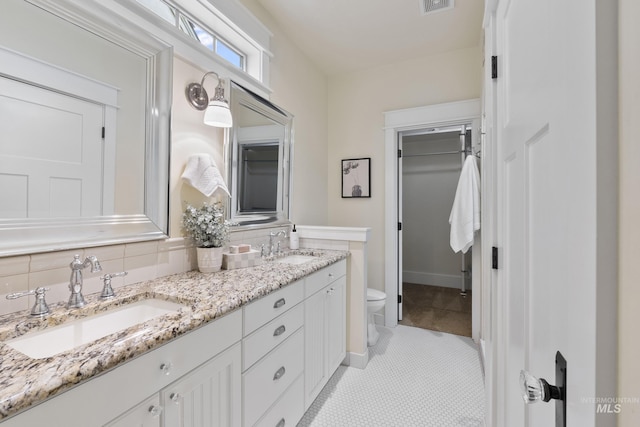 full bath with double vanity, a sink, a spacious closet, and toilet