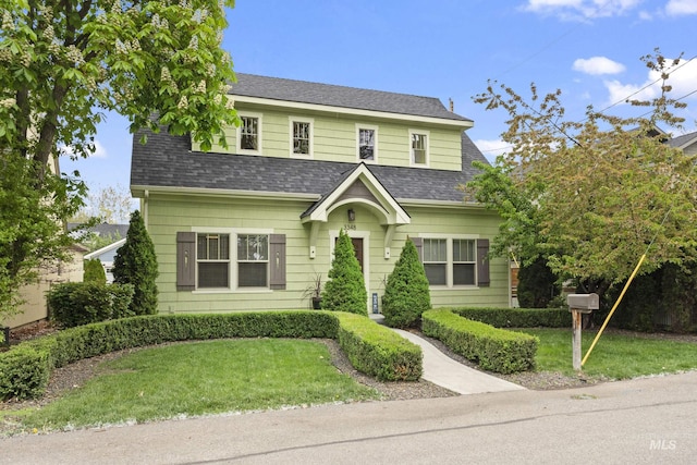 view of front of house featuring a shingled roof and a front yard