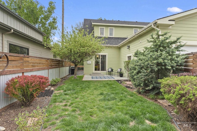 rear view of house featuring fence, a yard, a patio area, and roof with shingles