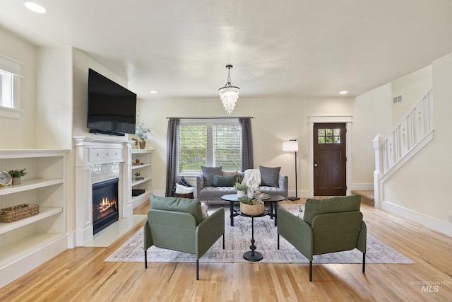 living area featuring a healthy amount of sunlight, a tiled fireplace, wood finished floors, and visible vents