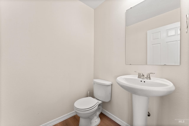 bathroom with toilet, wood finished floors, a sink, and baseboards