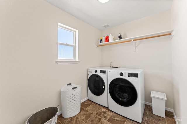 washroom with laundry area, washing machine and clothes dryer, and baseboards