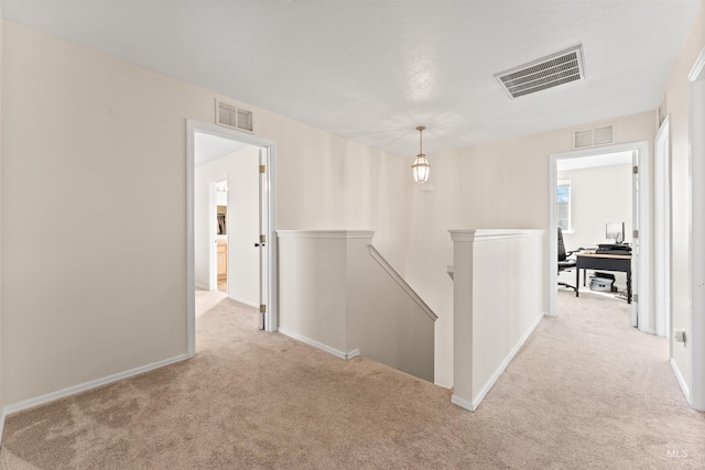 hallway featuring an upstairs landing, baseboards, carpet, and visible vents