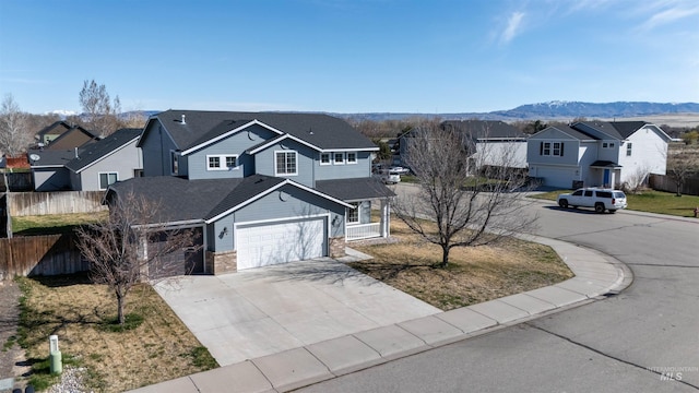 traditional-style house featuring a residential view, fence, an attached garage, a mountain view, and driveway