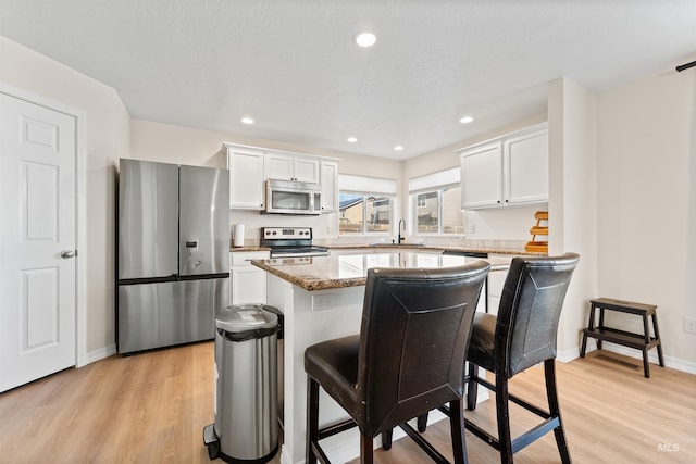 kitchen featuring light wood-type flooring, a center island, white cabinetry, and stainless steel appliances