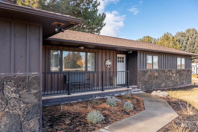 property entrance with covered porch, a shingled roof, and board and batten siding