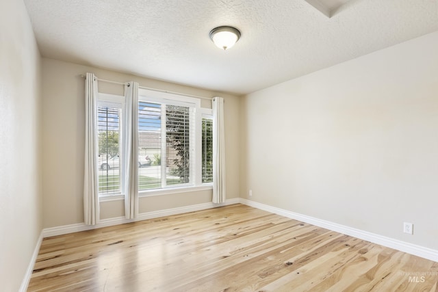 spare room with baseboards, a textured ceiling, and wood finished floors