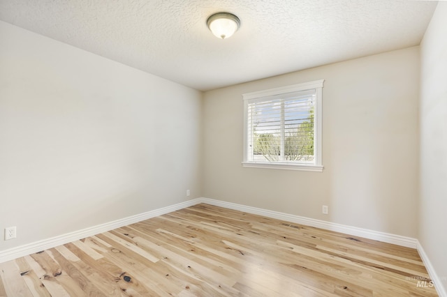 unfurnished room featuring baseboards, a textured ceiling, wood finished floors, and visible vents