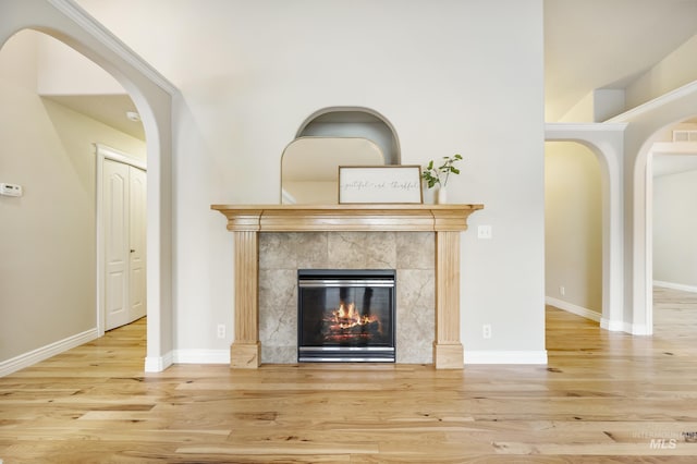 room details with arched walkways, baseboards, wood finished floors, and a premium fireplace